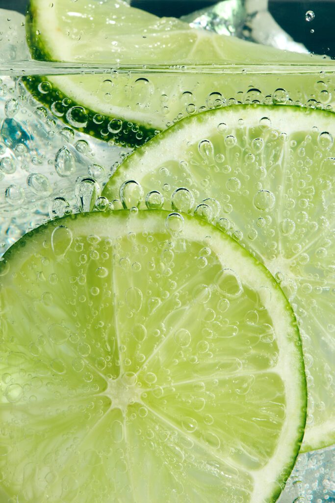 a diptych of Bombay Sapphire product shots, one flat lay of the bottle with limes around it, the other limes infused with the drink, surrounding bubbles. 