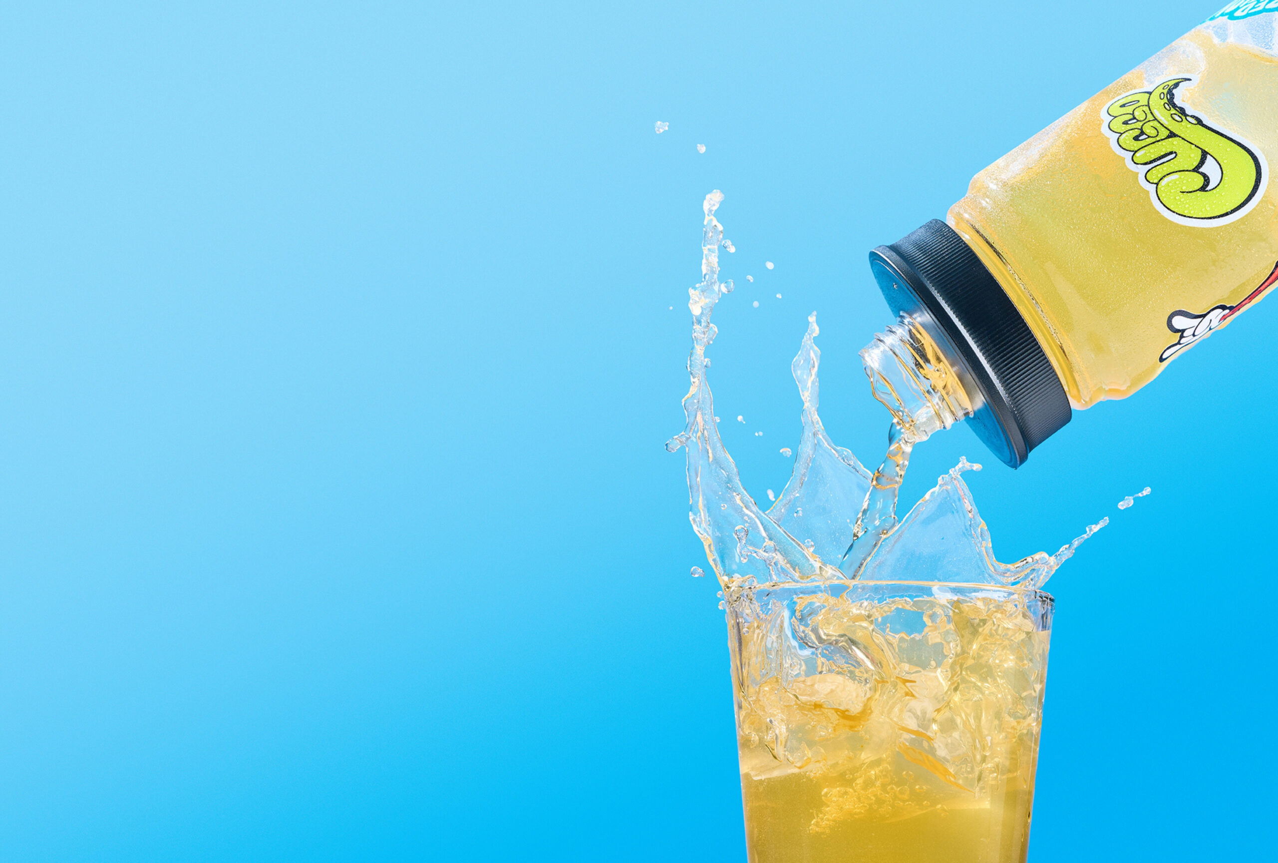 Water bottle pouring Crisp Apple Cuggo (a hydration drink for kids) into a glass with a large splash.
